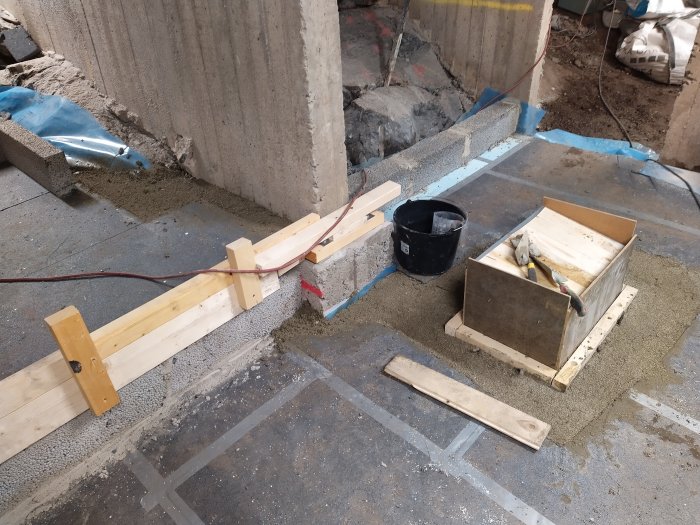 Renoveringsarbete med nylagt cement, träreglar, murhink och formar för gjutning.