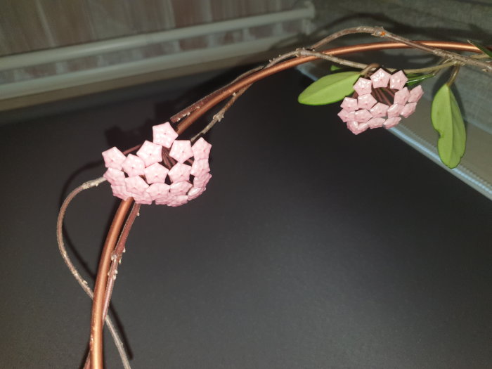 Konstgjorda rosa blommor och gröna blad på bruna grenar, inomhusdekoration.