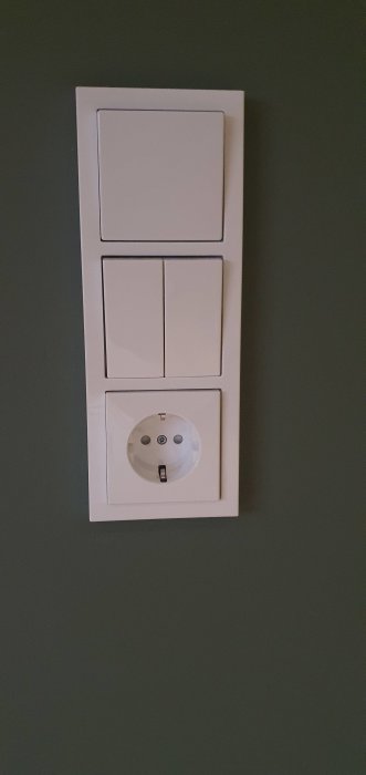 ABB Impressivo eluttag och strömbrytare monterade på en mörkgrön vägg, exemplifierar en väl genomförd elinstallation.