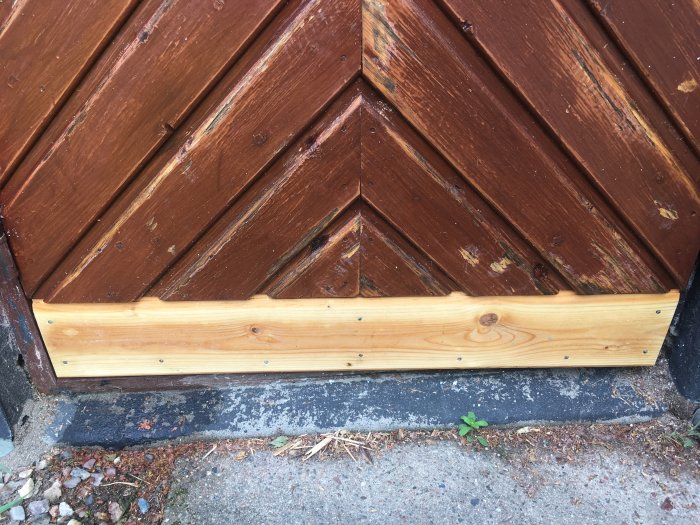 Nyhyvlad furupanel monterad som avslut på en äldre rödmålad fasad med diagonala panelbrädor.