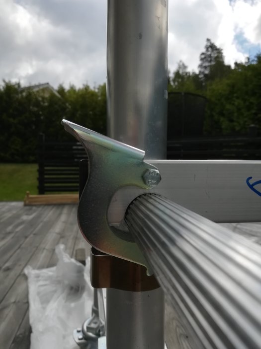 Delvis infäst stegeklo som inte passar helt över stege på byggarbetsplats.