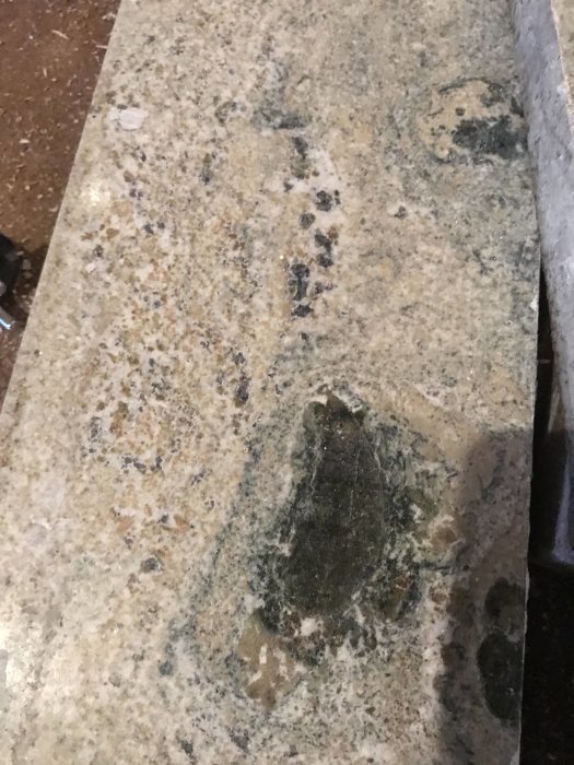 Närbild på en stenfönsterbänk med grå och svarta inslag som kan vara kolmårdsmarmor eller granit.