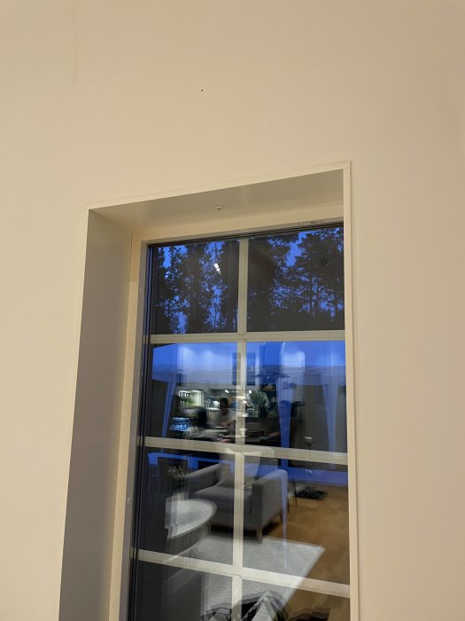 Dimly lit window with reflection of an interior room, suggesting malfunctioning timer-controlled lights.