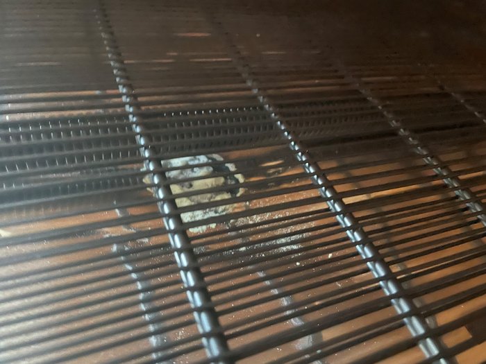 Kylskåps baksida med vitt skum och potentiella brännmärken på kylrören.