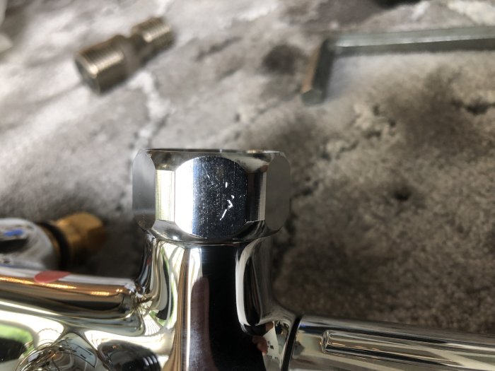 Närbild på en Grohe-blandares insexskruv och mutter som ska tas bort för montering av excenter.
