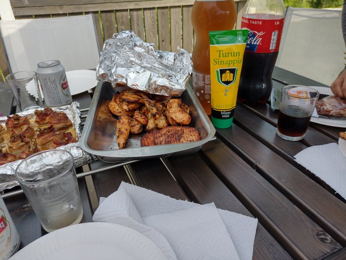 Midsommarmat på bord: grillad kyckling, baconlindad sparris, Turun sinappi, Coca-Cola och dryck i glas.