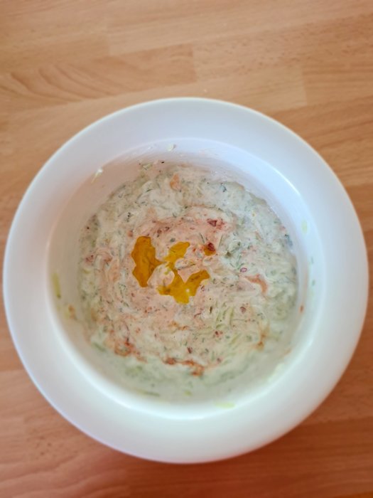 Hemlagad tzatziki med gurka, vitlök och olivolja i vit skål, toppad med röd Sambal Oelek.