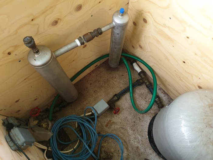 Vattenpumpssystem med filter och slangar i pumprum, användare osäker på installationen.