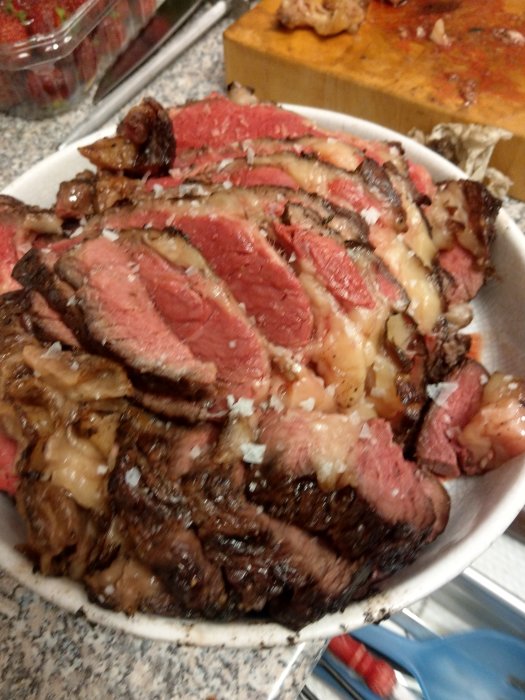 Skivat, rosa kött strimlat upp på en tallrik, kryddat med lök, efter att ha tillagats i en keramikgrill.