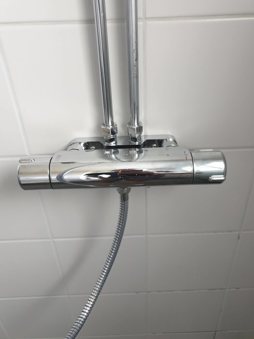 Duschtermostat kopplad till två rör på kakelvägg med synlig duschslang och löst termostathuv.