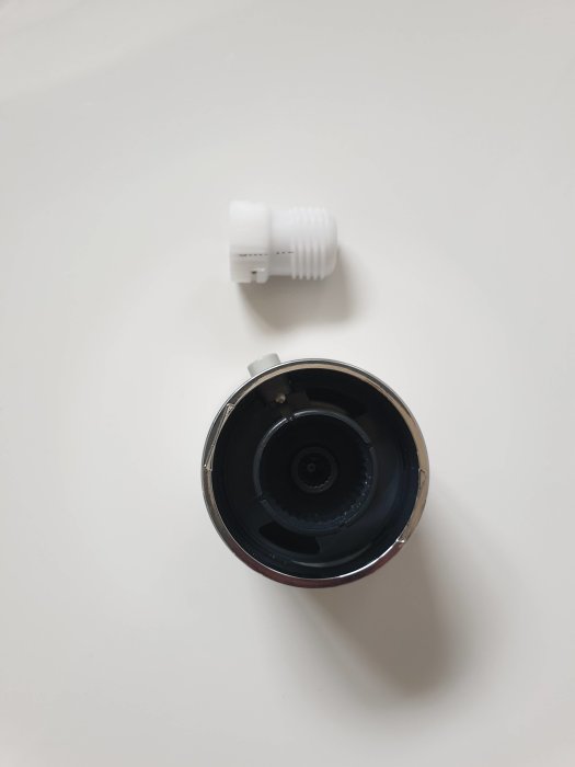 Vit plastdel av en blandare och en delvis monterad blandarkropp sett uppifrån.