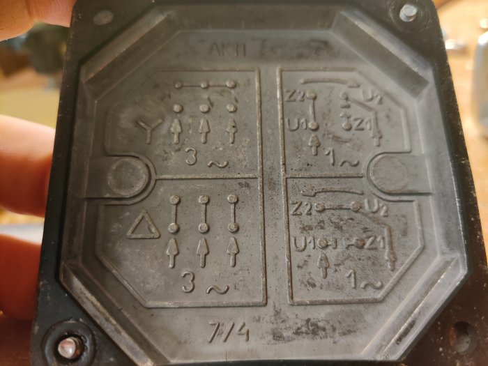 Närbild av en elmotorskylt med kopplingsscheman graverade på en metallplatta, visar Y- och Δ-konfigurationer.