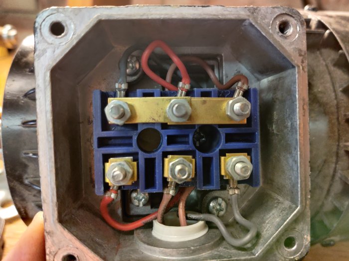 Närbild på ett öppet elektriskt kopplingsskåp för en bandsågsmotor med synliga kablar och anslutningar.
