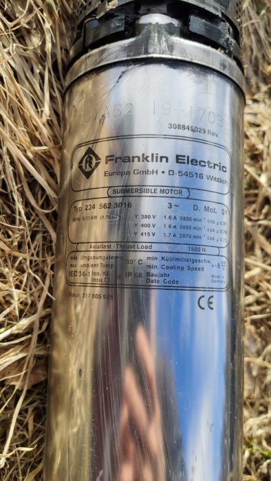 Närbild på en etikett på en 3-fas Franklin Electric submersibel pumpmotor utomhus.