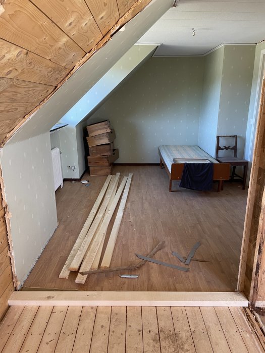 Pågående arbete med att regla upp en vägg i ett rum, träreglar på golvet och avrivna väggar syns.