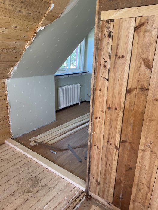 En regel på ett trägolv bredvid en vägg, ett pågående byggprojekt.