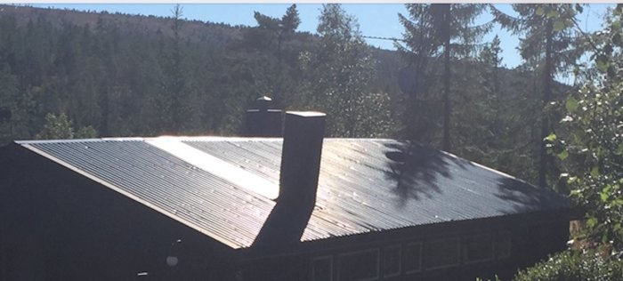 Lutande plåtskorsten på fjällstuga med snedbelastning från snötryck.