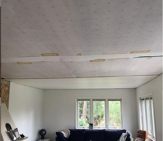 Loft med åndbar membran monteret under råspont, i en stue med vinduer mod en have.