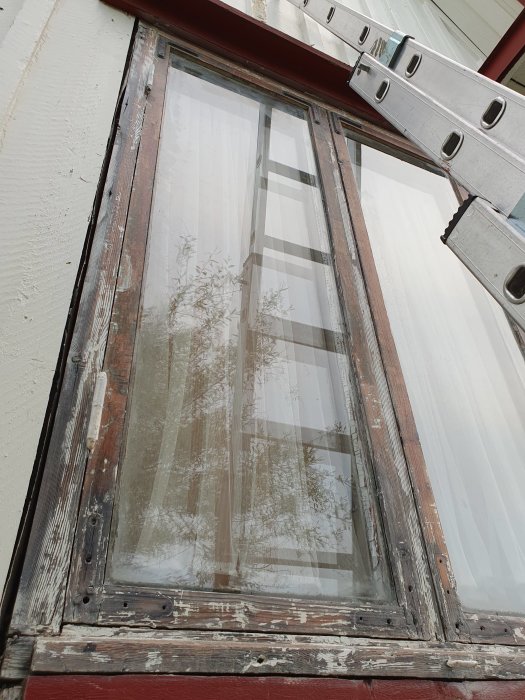 Ett fönster under renovering med borttaget silikonkitt och trädelar som förbereds för oljning.