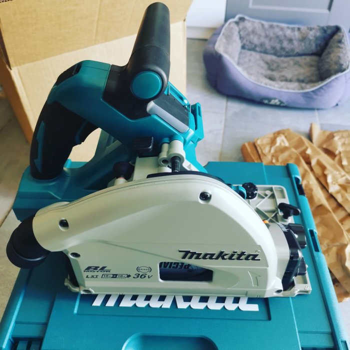 Ny Makita dyksåg på blå förvaringslåda med hundbädd i bakgrunden.
