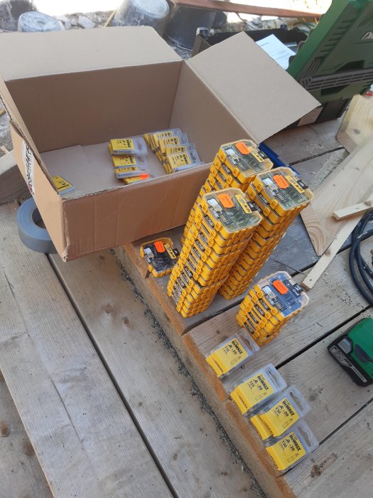 Öppen låda med många paket av bits på en träyta vid en byggarbetsplats.