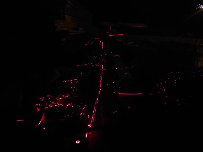 Mörk bild av ett byggprojekt med markerade linjer från en krysslaser på träreglar och underlag under kvällstid.