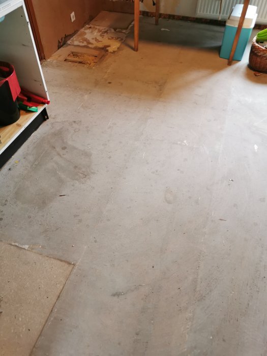 Ojämnt undergolv med spånskivor och synliga limrester i en renoveringsmiljö.