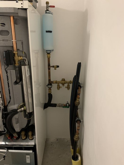 Installation i pannrum med expansionskärl, kopparledningar och värmesystemskomponenter.