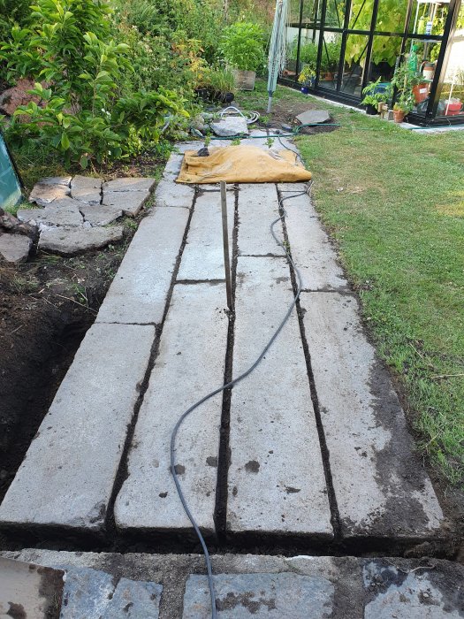 Granitstenblock med slät yta, upplagda på marken, 15 cm tjocka, i en trädgård.