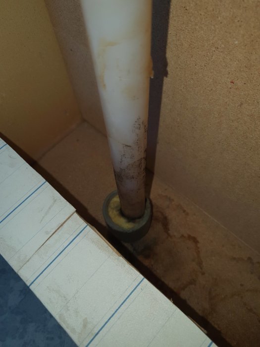 Vattenrör i hörn med mögel och rostfläckar, kondenssynliga på vägg och golv i tvättstuga.