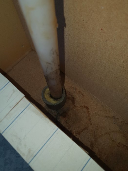 Vattenrör i skåp med mögel och kondens på en våt och fläckig vägg och golv.