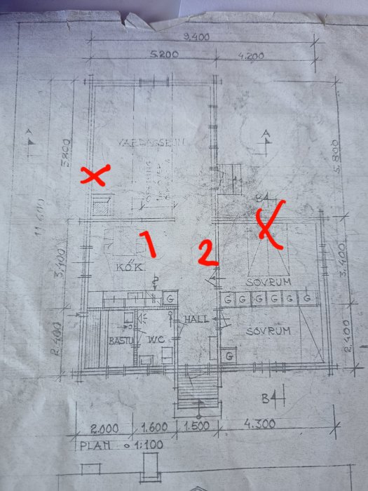 Arkitektritning av husplan med markerade väggar "1" och "2" och planerade fönsterpositioner med röda "X".