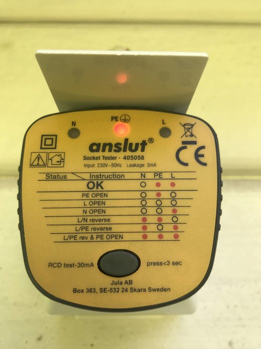 Uttagsprovare insatt i vägguttag med lysande indikatorlampor, visar felstatus L/N reverse.