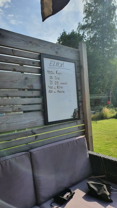 Whiteboard med träningsprogram utomhus, innehållande löpning, hopp och rodd.