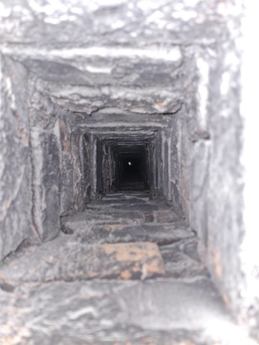 Gammal mörk rökkanal sedd inifrån, suddiga väggar som smalnar av mot en ljuspunkt i bakgrunden.