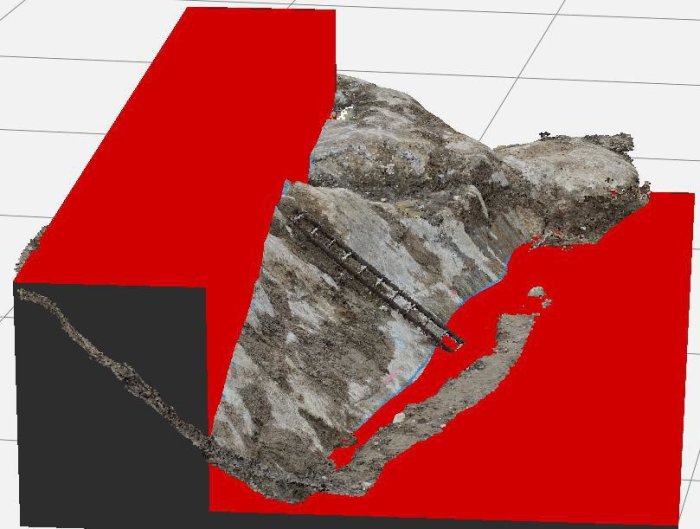 3D-planering av sprängningsarbete på en tomt markerad med röd färg runt grå bergyta med inslag av blå linjer.