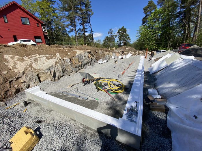 Pågående arbete med kantbalkar på en byggarbetsplats, material och verktyg utspridda på grusunderlag.