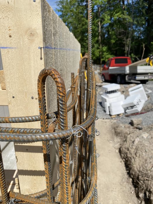 Armeringsjärn och brädform för platsgjutning av stödmur i byggprojekt utomhus.