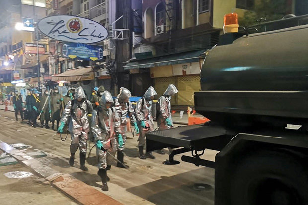 Arbetare i skyddsdräkter besprutar gator i Bangkok nattetid med desinfektionsmedel under Covid-19 pandemin.