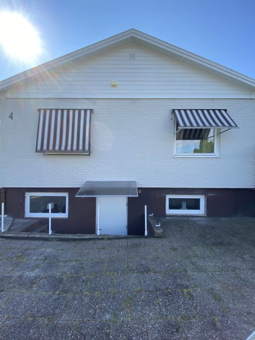 Husgrund före målning med reparerade ojämnheter, vita väggar och mörk sockel.