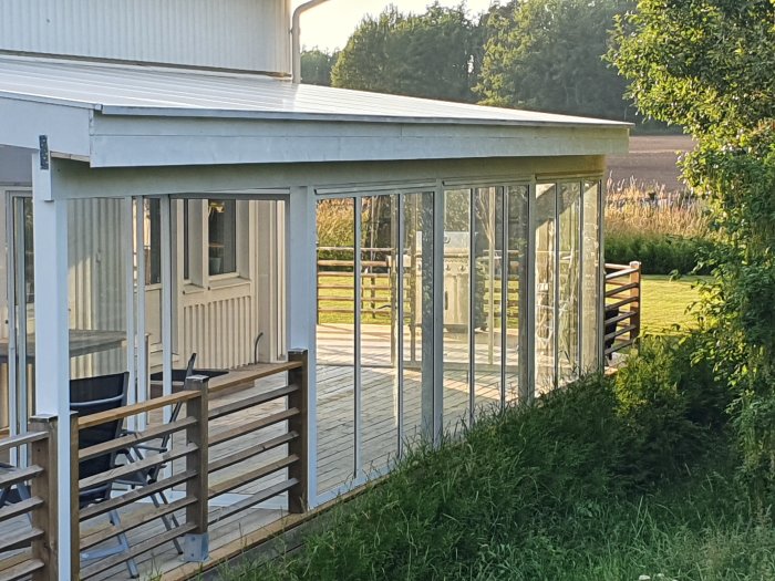 Nyinstallerad vit vattbräda och takfot på ett uterum vid ett hus, nyligen målat, med omgivande trädgård.