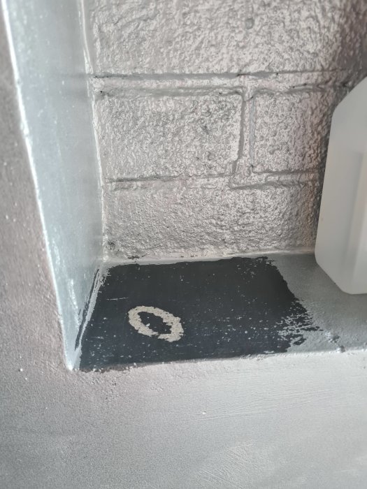 Vägg med avskalad färg i en cirkel på en svartmålad yta som skadats av myggmedel.