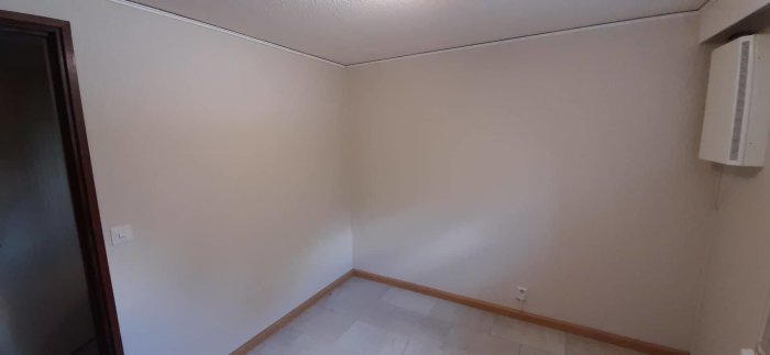 Renoverat rum med släta, nymålade väggar, taklister och en värmeelement på väggen.