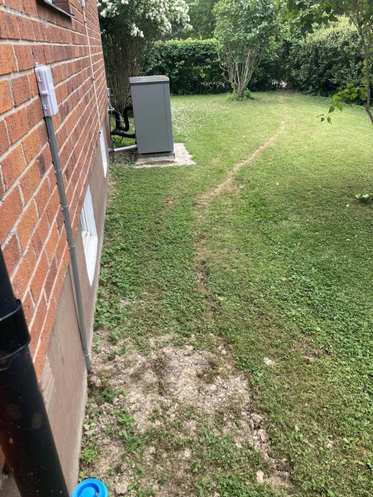 Grävmärken i en trädgård som visar var fiberoptisk kabel har dragits fram till en fasadbox.