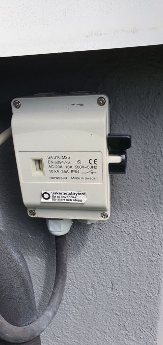 Säkerhetsbrytare monterad på vägg med tekniska specifikationer, märkt "Made in Sweden".