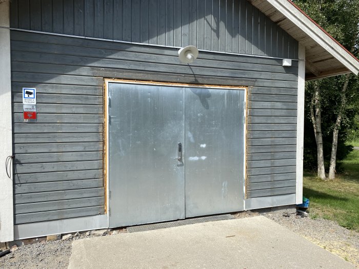 Ett grått garage med en stängd slagport markerad med röda strecken där porten skall ersättas med en rullport.
