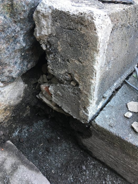 Betongtrappa med ett hål vid sidan där tidigare tegelsten och betong har separerats och spruckit.