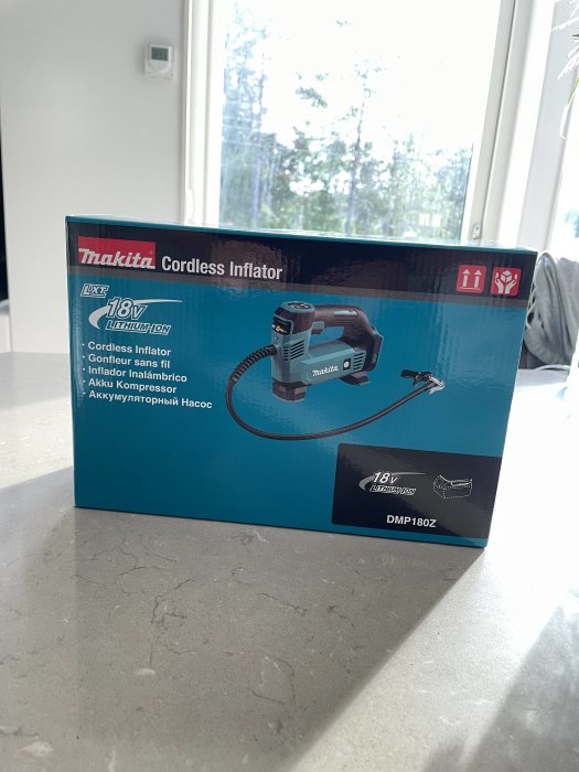 Förpackning av en Makita 18V uppladdningsbar sladdlös inflator på ett köksbord.