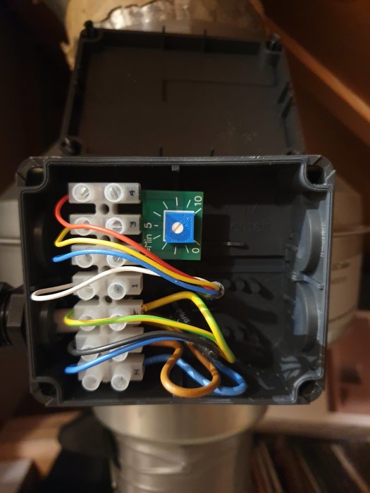 Öppen elektrisk anslutningsbox med fläktens kablar och intern potentiometer synliga.