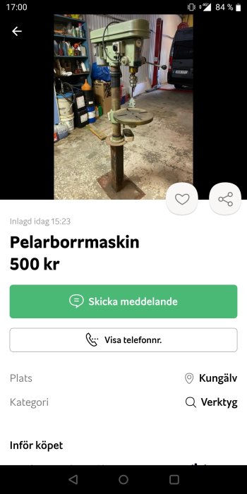 Pelarborrmaskin till salu i garage, med hyllor och oljeflaskor i bakgrunden.